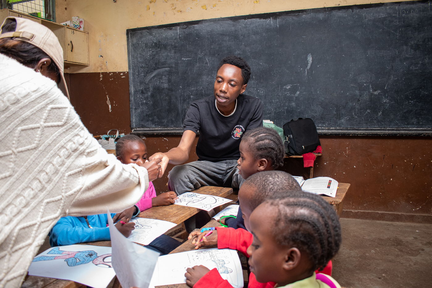 Children and volunteers around desks in a classroom during the creative stations