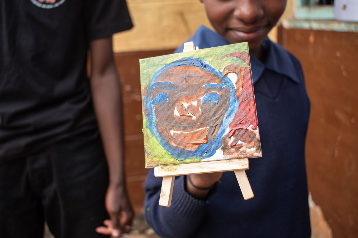 A child holding up a painted canvas