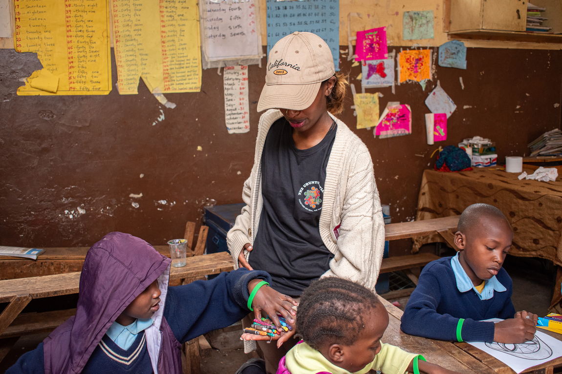 An adult helping children at a desk