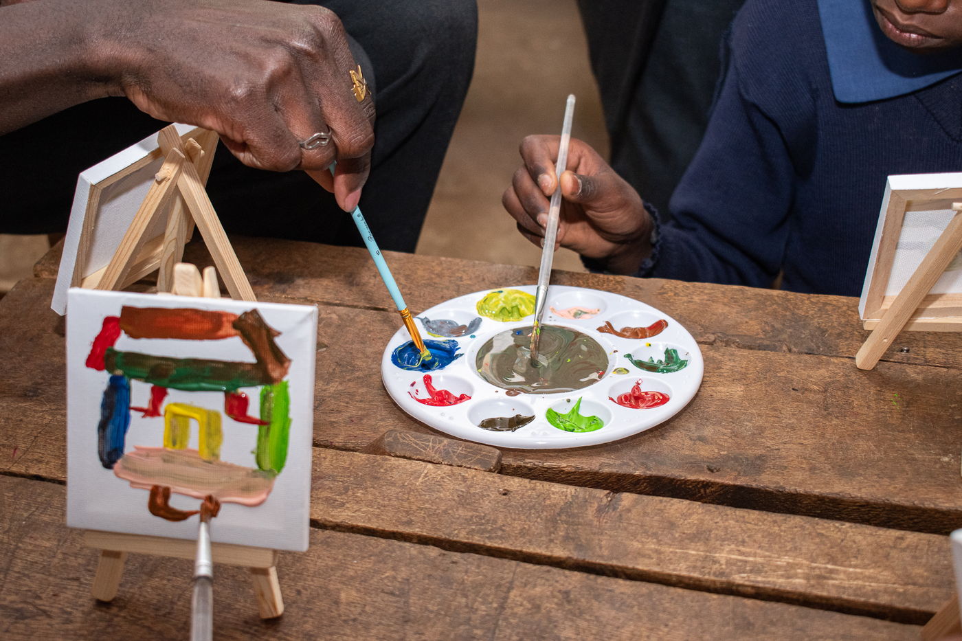 A child painting a small canvas on a wooden easel