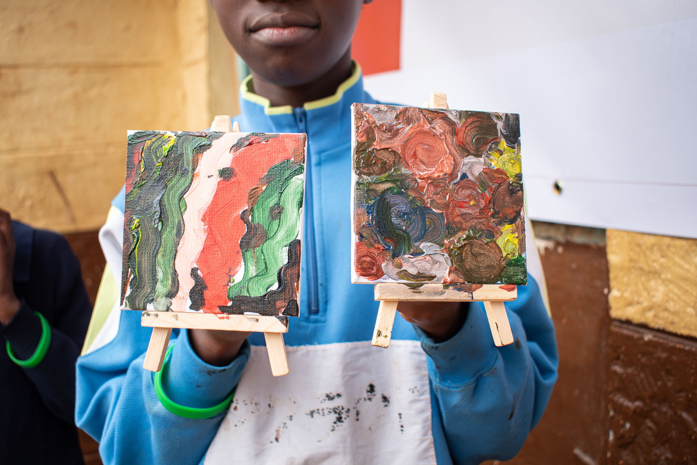 A child holding up two finished canvas paintings